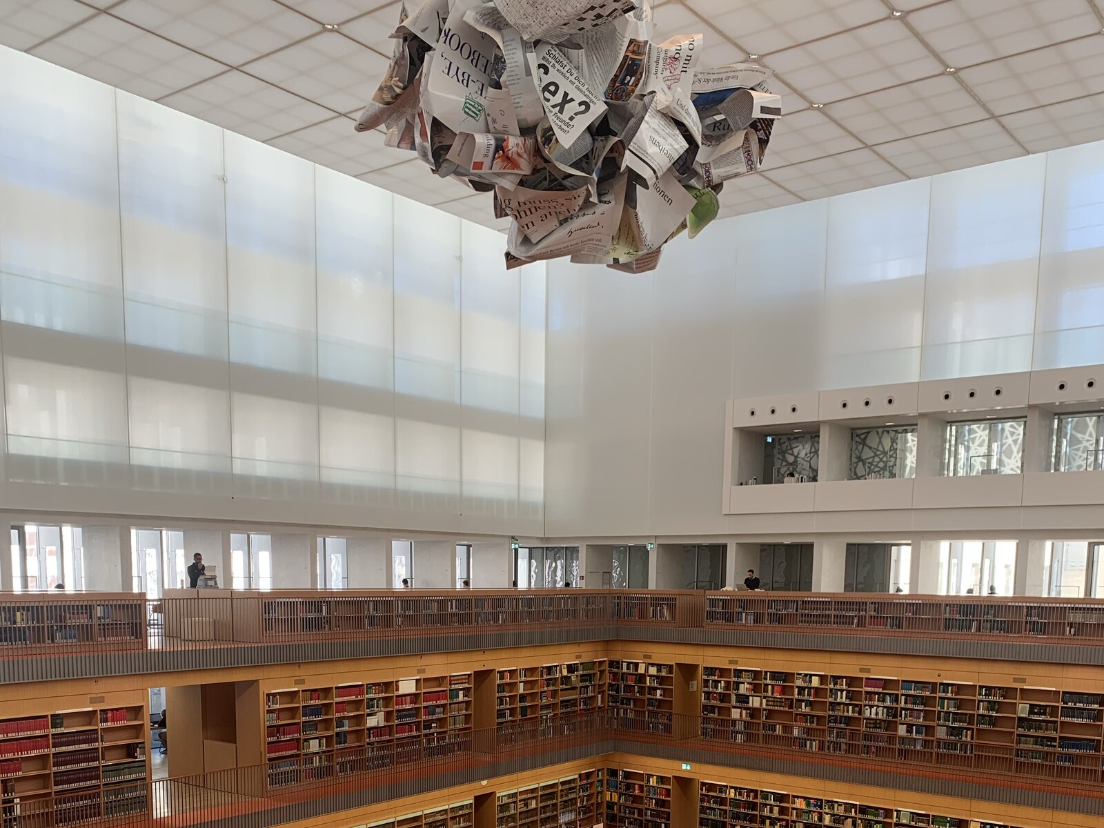 The skylit roof and hanging sculpture above the reading room of the Berlin State Library, with the top balcony of bookshelves below.